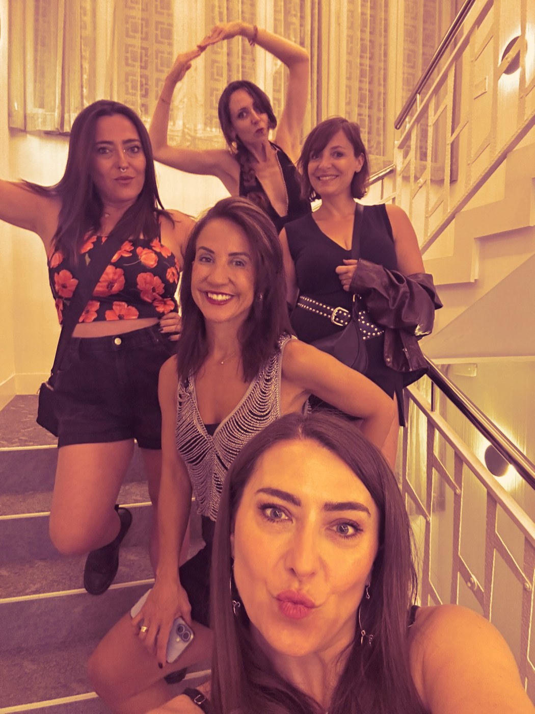Five women laughing and posing together on a staircase